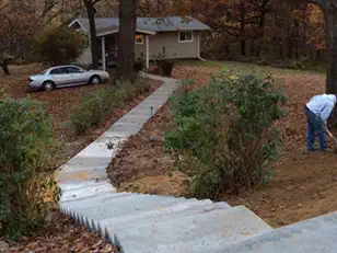 Poured concrete steps and walk winding down a wooded slope to a house