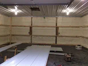 Spray foam insulation between the girts of a building under construction