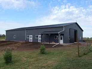 Gray steel horse barn with Dutch stall doors and a covered entry, built by Path Construction