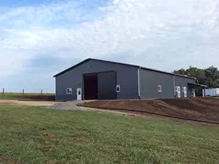 End wall of a gray horse barn with a large sliding door