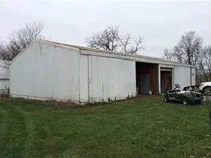 Old white machine shed with worn siding