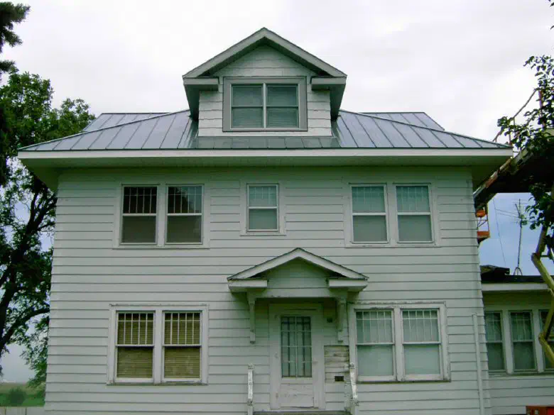 Front of the farmhouse with its new metal roof and dormer