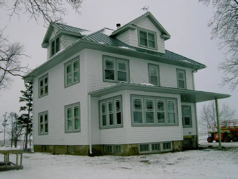 Side of the farmhouse with the new roof and sunporch