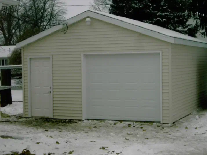 Tan sided single-stall garage in the snow